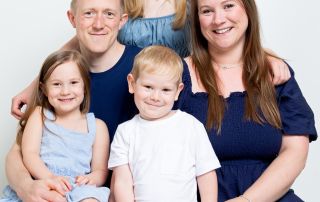 A family of two adults and three children dressed in matching shades of blue and white