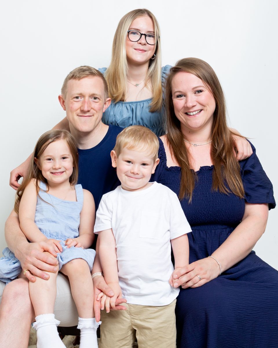 A family of two adults and three children dressed in matching shades of blue and white