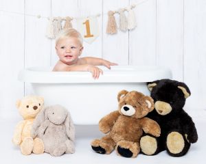 First Birthday Photo Shoot West Sussex a little boy in a bathtub with teddy bears sitting beside him