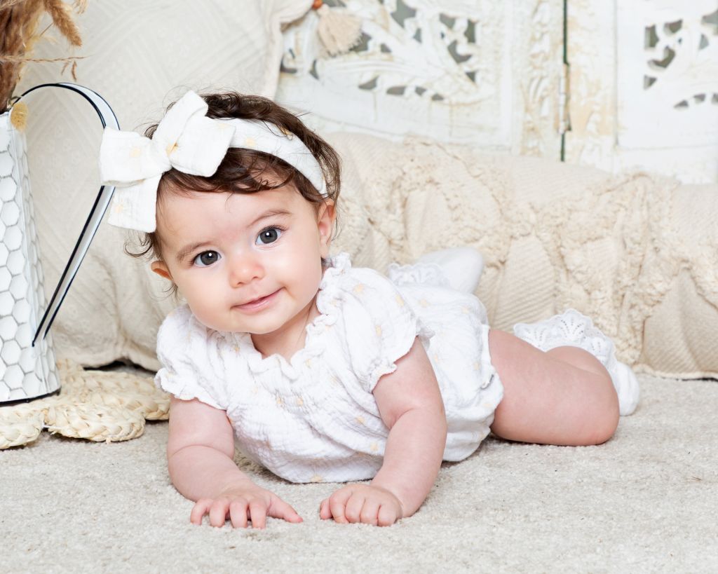 Baby Photography West Sussex a little girl with dark hair and brown eyes poses in a Boho Styled studio set