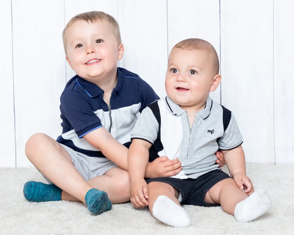 Two brothers pose together in a photo shoot in similar blue thsirts