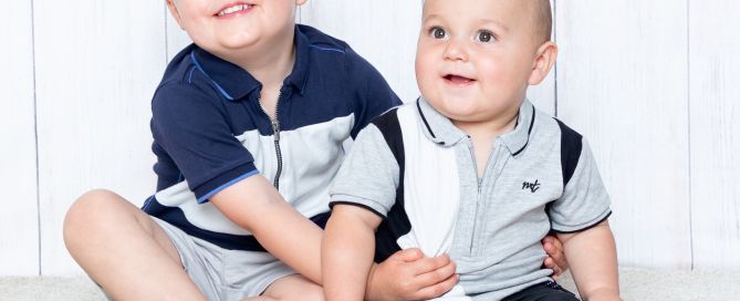 Two brothers pose together in a photo shoot in similar blue thsirts