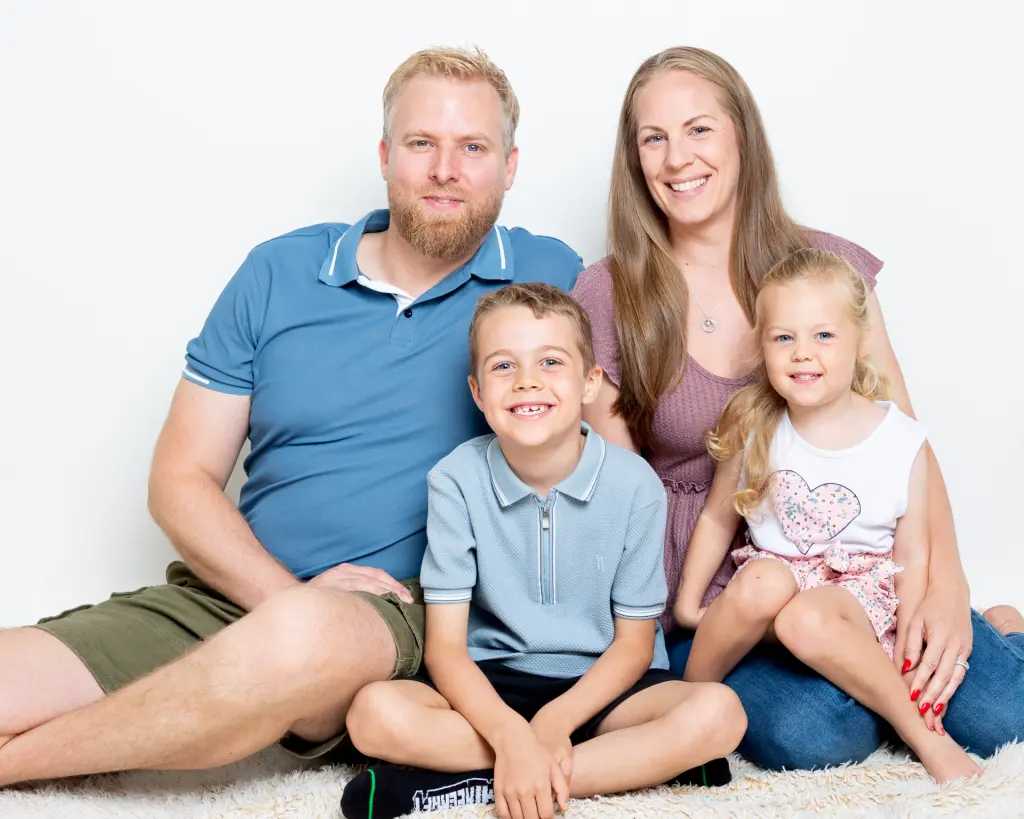 A family pose together sitting on the floor with parents and two children at my studio in Sussex