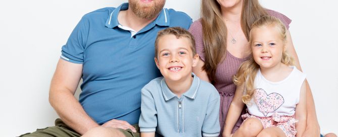 A family pose together sitting on the floor with parents and two children at my studio in Sussex