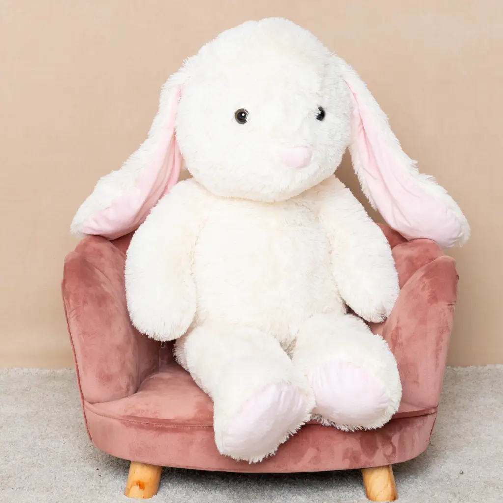 a giant plus rabbit sits on a pink chair in the studio