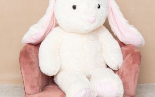 a giant plus rabbit sits on a pink chair in the studio