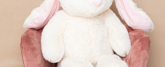 a giant plus rabbit sits on a pink chair in the studio