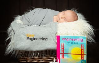 A baby sleeps by a branded tshirt for an engineering company his parents work for.