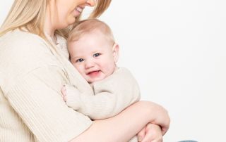 A mum sits with her baby boy on her lap giving him a big cuddle at a west sussex photo shoot