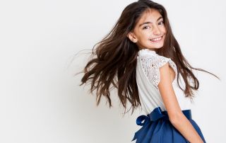 a girl flings her hair plays with a white dress at west sussex fine art children's photography session