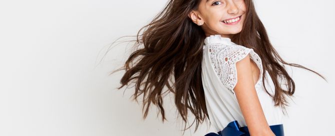 a girl flings her hair plays with a white dress at west sussex fine art children's photography session