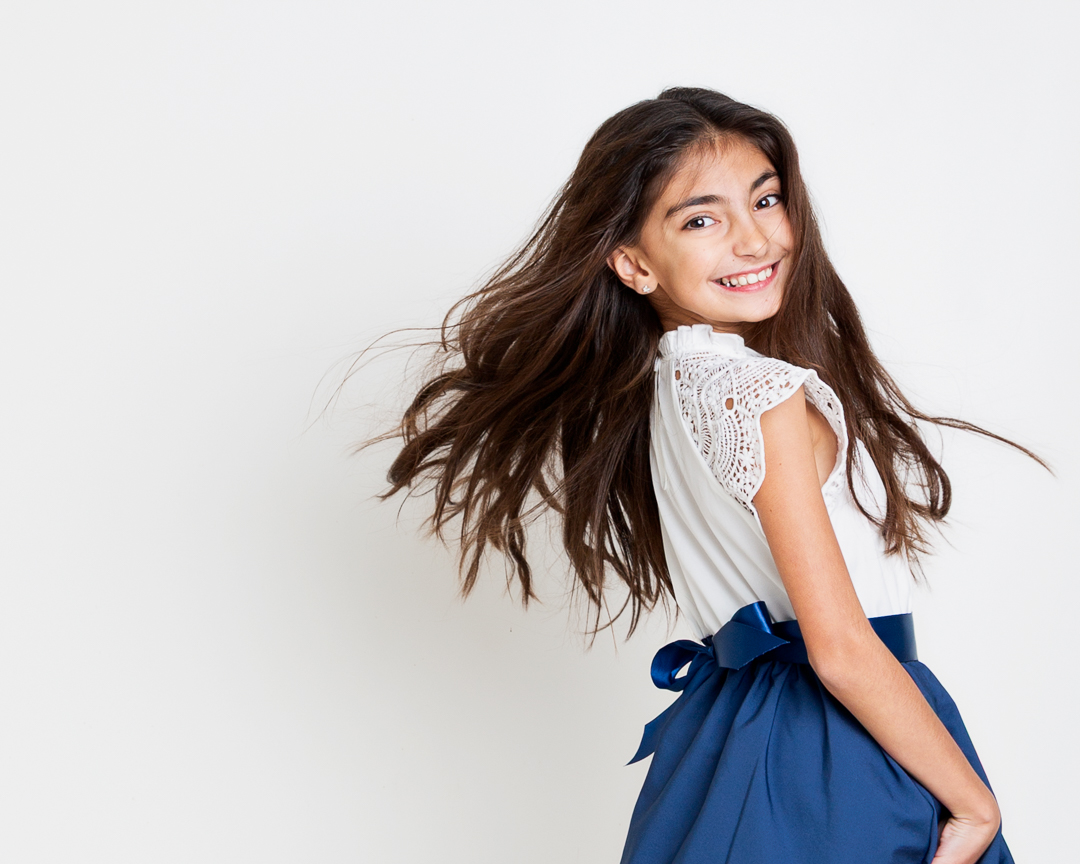 a girl flings her hair plays with a white dress at west sussex fine art children's photography session