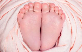 Pair of newborn feet wrapped in peach fabric