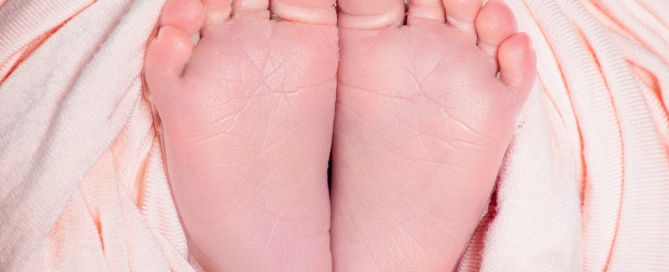 Pair of newborn feet wrapped in peach fabric