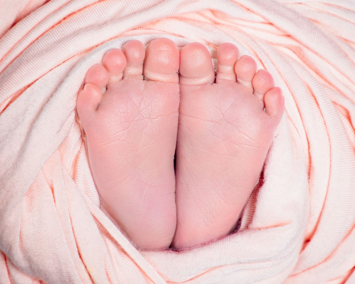 Pair of newborn feet wrapped in peach fabric