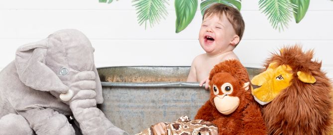 A little boy has a great time in a tub surrounded by jungle props