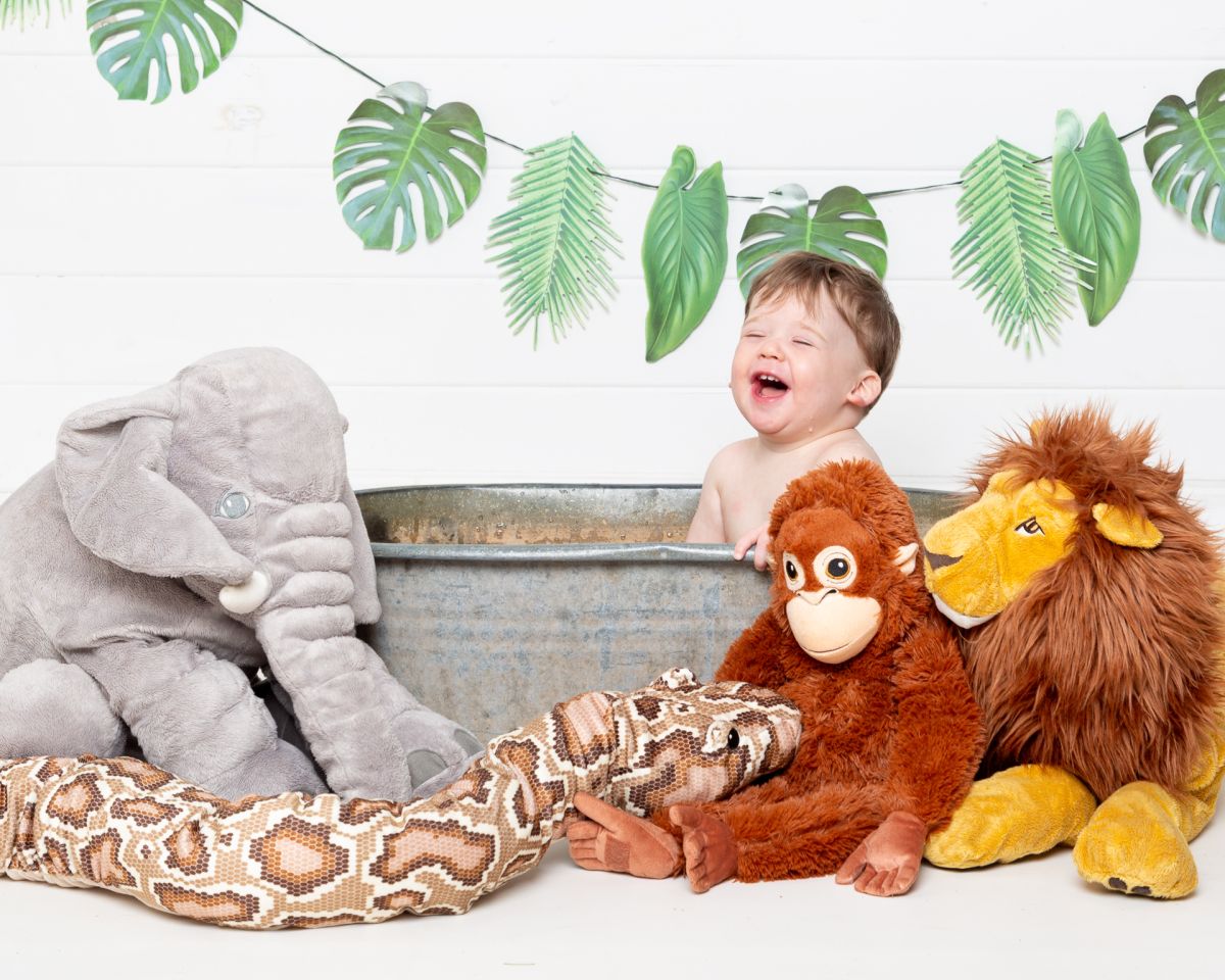 A little boy has a great time in a tub surrounded by jungle props