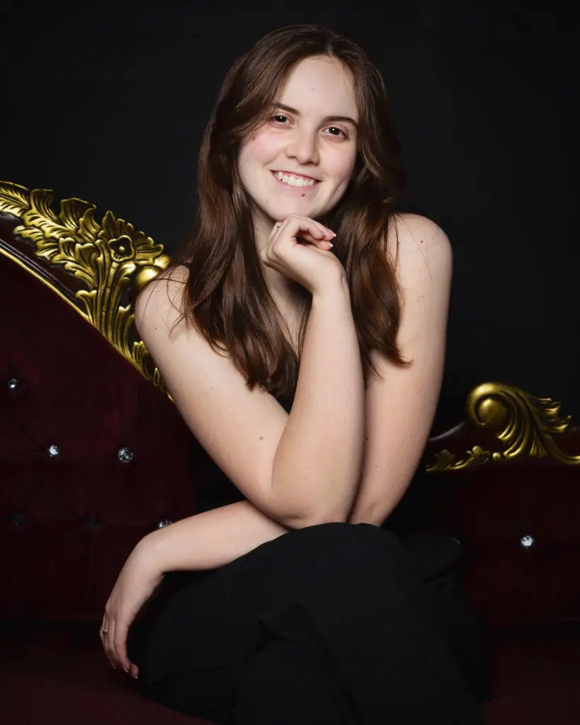 A teenage girl poses for a photograph on a chaise