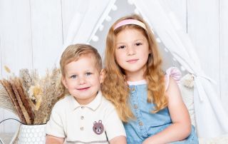 a brother and sister pose together outside a Boho styled tent