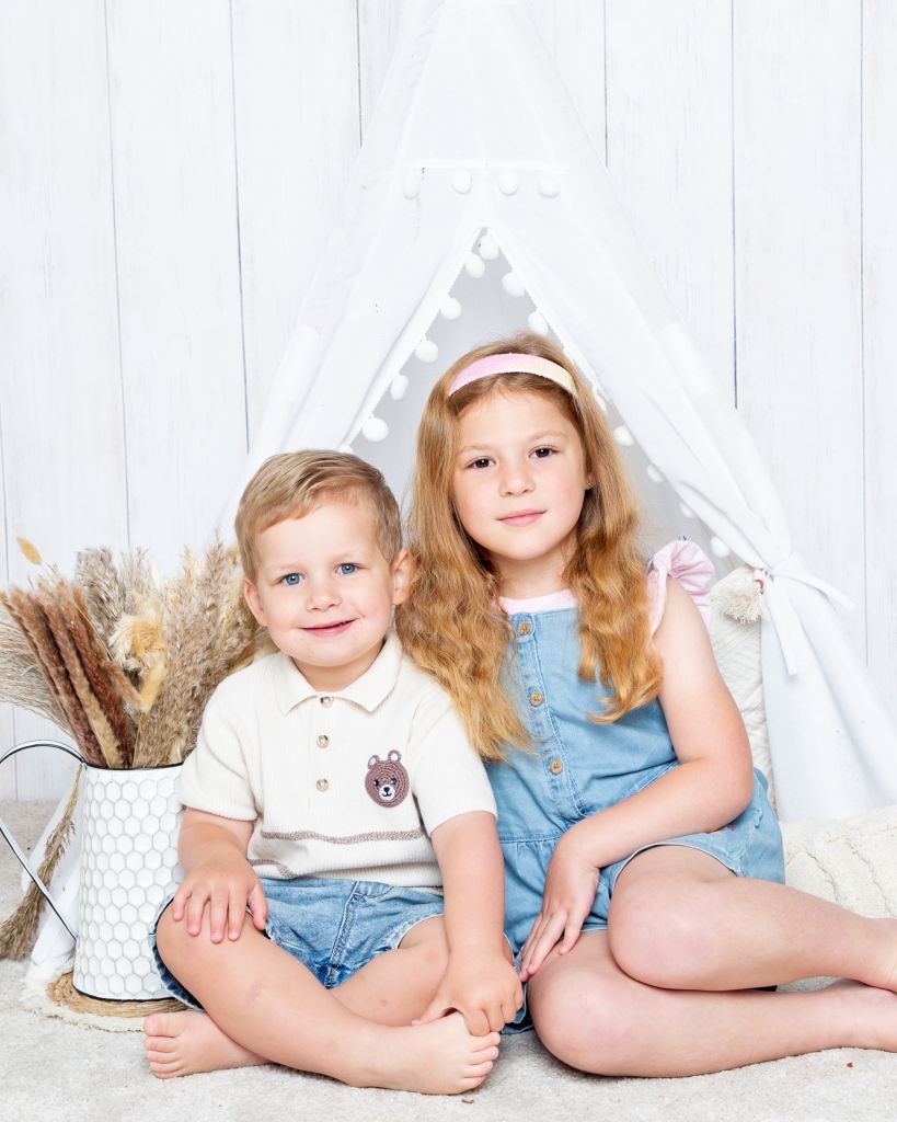 a brother and sister pose together outside a Boho styled tent