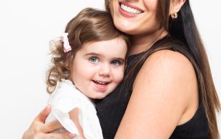 A picture of a mum and her daughter cuddling and smiling at the camera