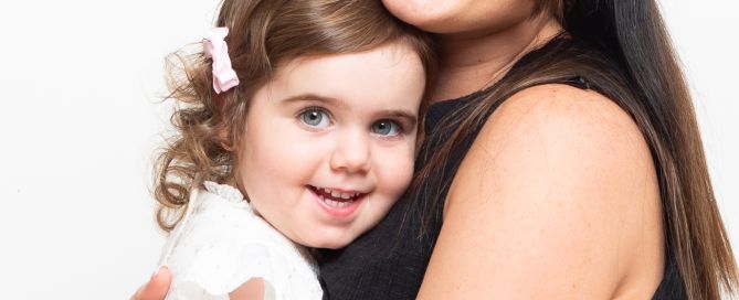 A picture of a mum and her daughter cuddling and smiling at the camera