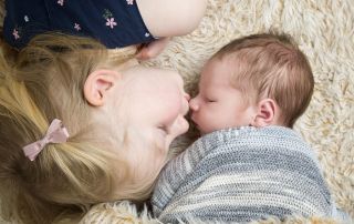 a big sister kisses her newborn baby brother