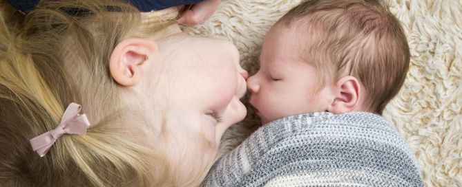 a big sister kisses her newborn baby brother