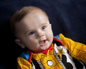 a baby dressed in a Woody outfit poses for a photo at a professional session