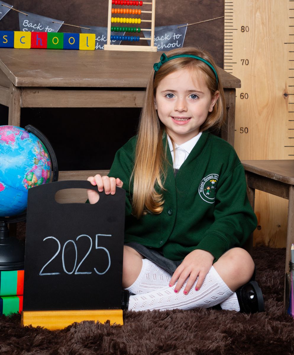 A little girl poses in a green jumper at a Starting School Photo shoot in West Sussex
