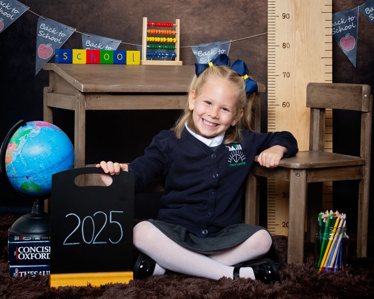 A little girl poses by a chair at a Starting School Photo shoot in West Sussex