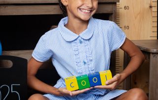 A little girl poses with blocks at a Starting School Photo shoot in West Sussex