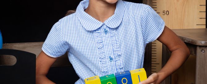 A little girl poses with blocks at a Starting School Photo shoot in West Sussex