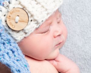 a newborn baby sleeps wearing an elf hat in blue and cream
