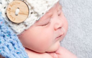 a newborn baby sleeps wearing an elf hat in blue and cream