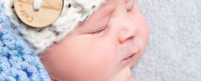 a newborn baby sleeps wearing an elf hat in blue and cream