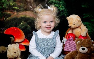 a little girl smiles in a teddy bears picnic themed set in the studio
