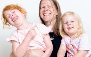 a mother and her two daughters laugh a family portrait session