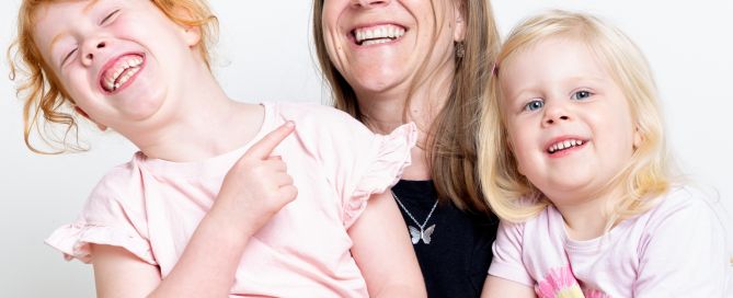 a mother and her two daughters laugh a family portrait session