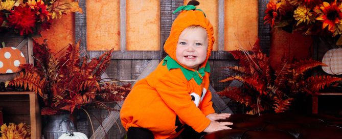 a little boy dressed as a pumpkin at a autumn themed photo shoot