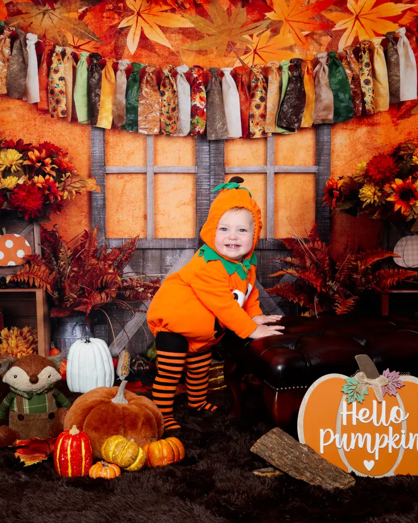 a little boy dressed as a pumpkin at a autumn themed photo shoot
