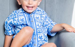 a little boy in a blue and white holiday outfit with a tan and blonde hair