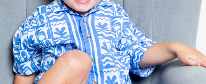 a little boy in a blue and white holiday outfit with a tan and blonde hair