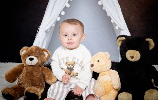 a little boy poses with teddy bears in a matching bear jumper