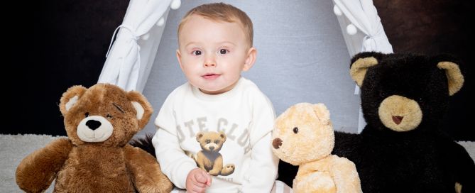 a little boy poses with teddy bears in a matching bear jumper