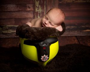 a newborn sleeps inside a fireman's helmet