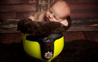 a newborn sleeps inside a fireman's helmet