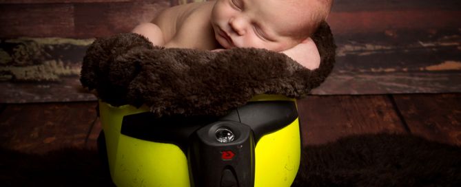 a newborn sleeps inside a fireman's helmet