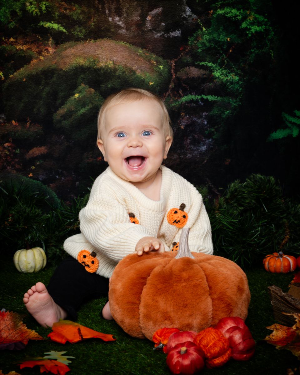 a little boy is smiling holding a fluffy pumpkin