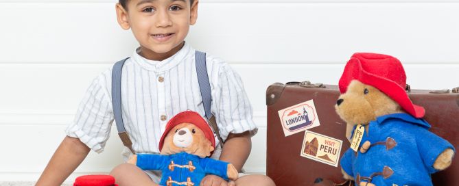 a little boy with toy Paddington bears and some themed accessories at a photo shoot